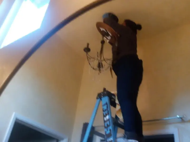 Electrician installing a chandelier in a Helena residence